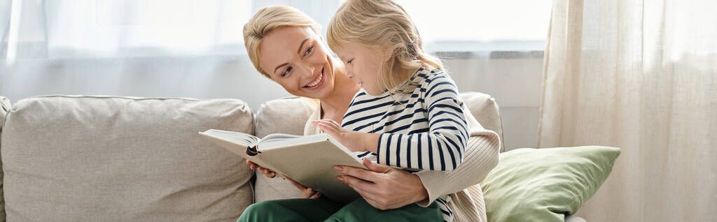 alegre chica sentado en vueltas de rubia madre y leer libro juntos en sala de estar, pancarta - Foto, imagen