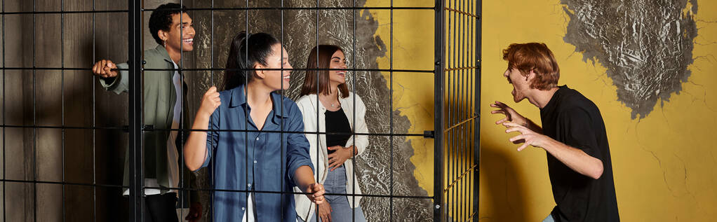 Kaçış odasında oyun sırasında çok kültürlü arkadaşlarını kilitli kafesin içinde korkutan adamın afişi. - Fotoğraf, Görsel