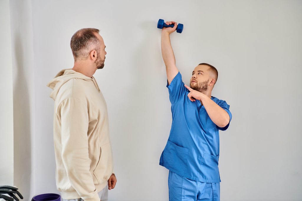 szakképzett rehabilitológus mutatja testmozgás súlyzóval, hogy a beteg helyreállítási kinesio központ - Fotó, kép