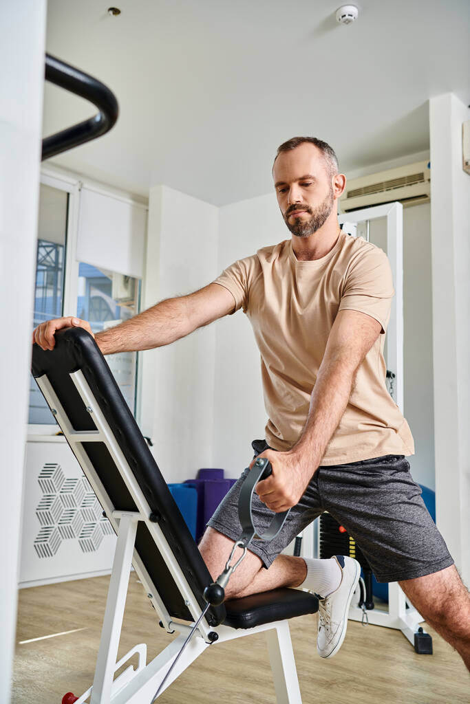 pohledný muž ve sportovním tréninku na cvičebním stroji v moderní tělocvičně kinezio centra, zotavení - Fotografie, Obrázek
