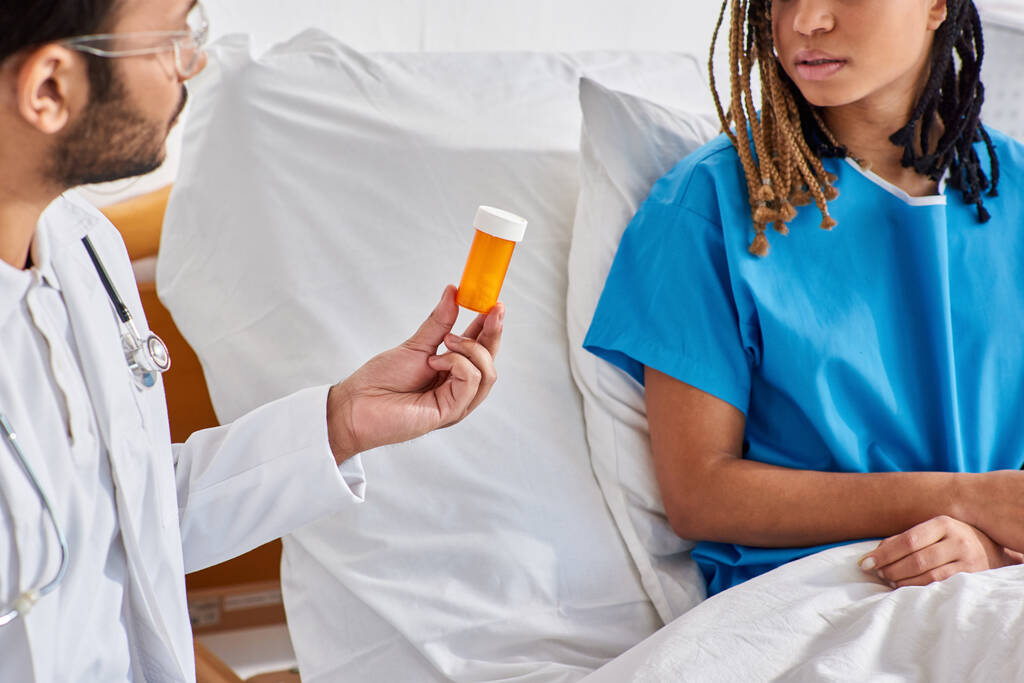 femme afro-américaine malade regardant son médecin indien lui donner des pilules alors qu'elle était à l'hôpital - Photo, image