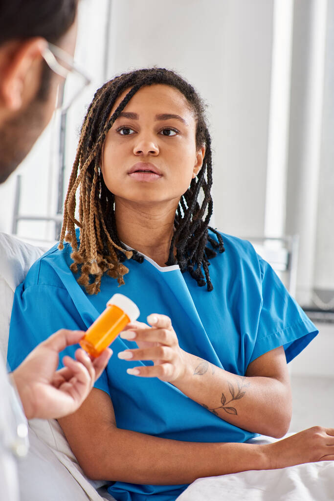 зосередитися на хворобі афроамериканки в лікарняному ліжку, приймаючи таблетки від її розмитого індійського лікаря - Фото, зображення