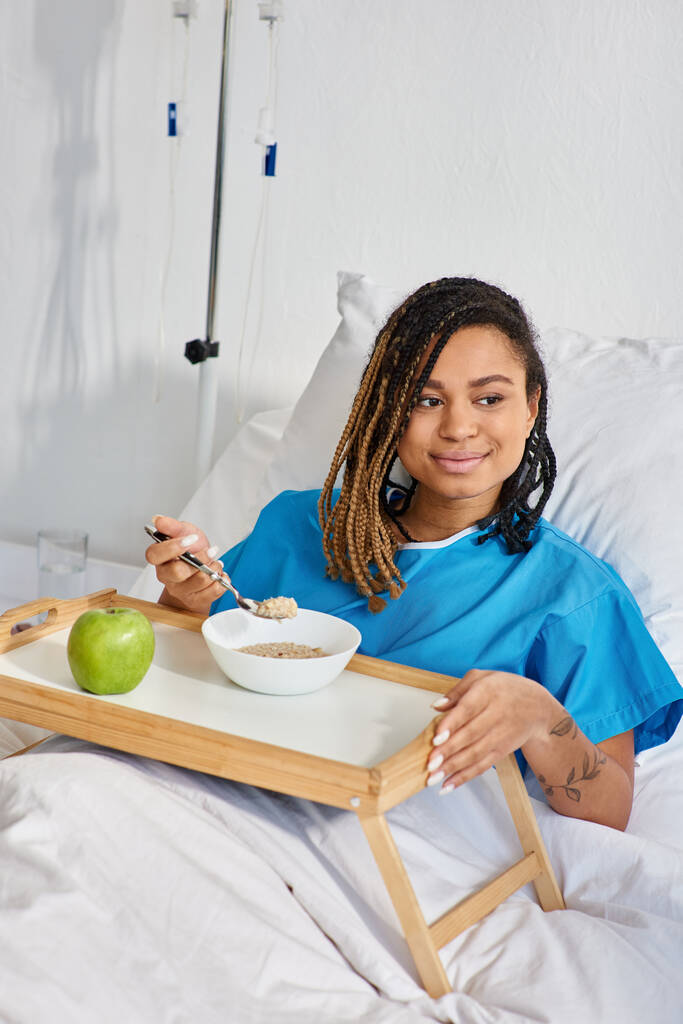 Afrykańska amerykanka jedząca owsiankę i jabłko na śniadanie w szpitalu, opieka zdrowotna - Zdjęcie, obraz