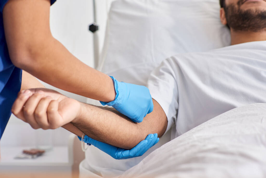 vista recortada de enfermera afroamericana insertando catéter en el brazo de su paciente indio, cuidado de la salud - Foto, Imagen