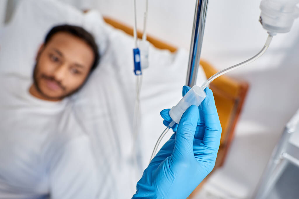 enfoque en la enfermera afroamericana estableciendo mostrador de gota junto al hombre borroso acostado en la cama de hospital - Foto, imagen