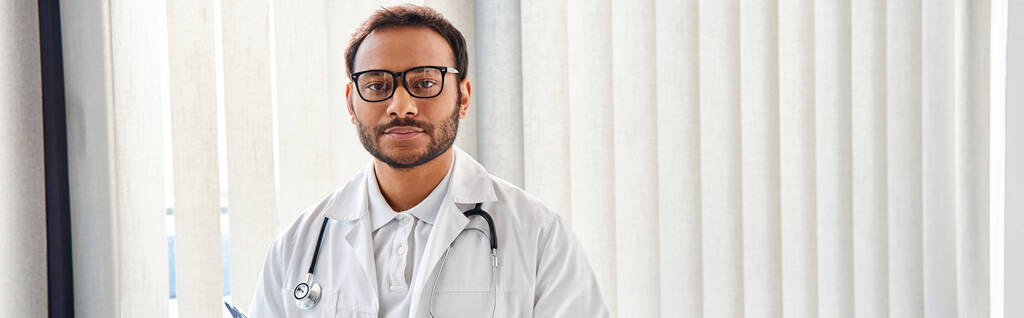 indian doctor with glasses and stethoscope in hospital ward looking at camera, healthcare, banner - Photo, Image
