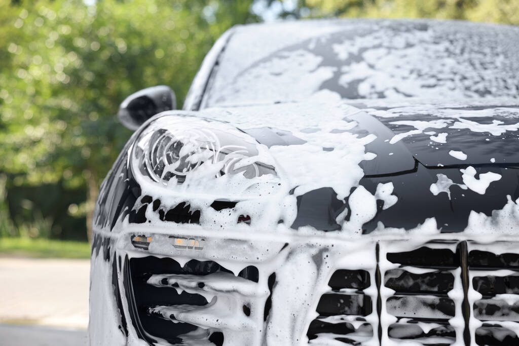 Auto covered with cleaning foam at outdoor car wash, close seup - Фото, изображение