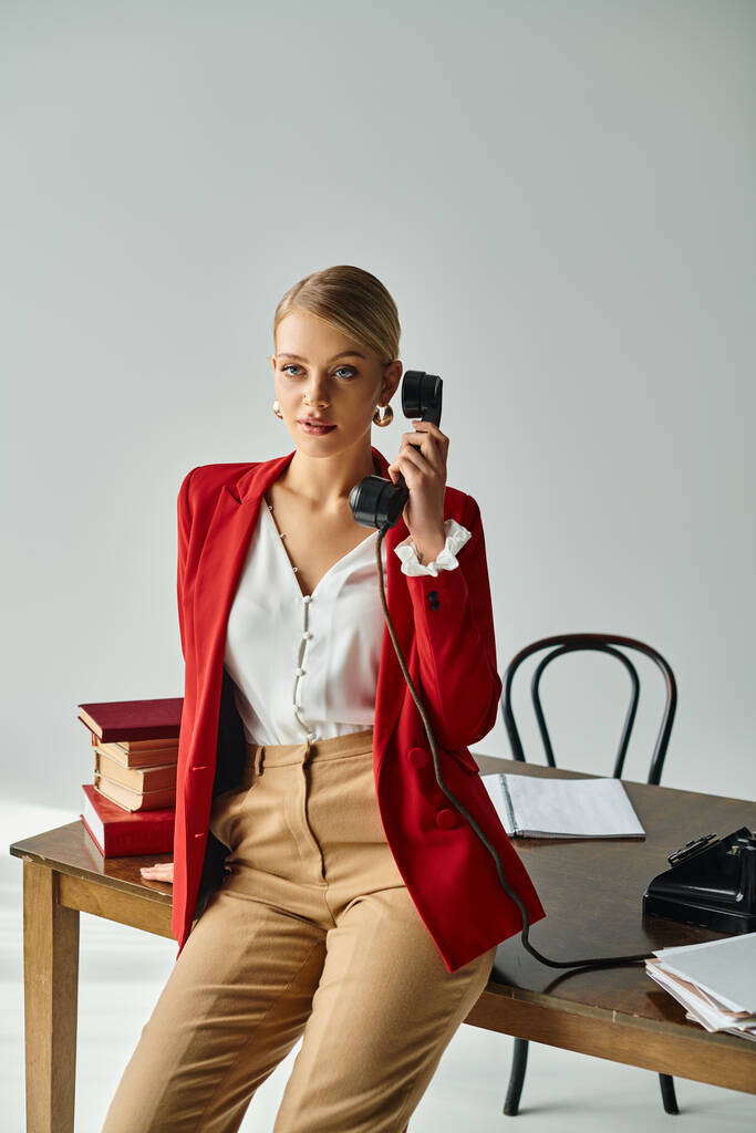 goed uitziende blonde vrouw in levendige kledij praten door retro telefoon en weg te kijken in het kantoor - Foto, afbeelding