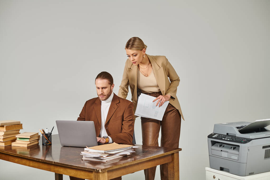 atrakcyjna blondynka z papierkową robotą w ręku patrząc na laptopa swoich chłopaków, romans w pracy - Zdjęcie, obraz