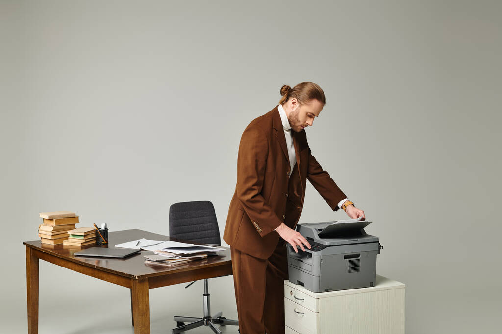 attractive young man with beard and collected hair in fashionable jacket working with copy machine - Photo, Image