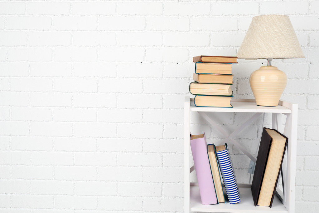 Dřevěná police s knihami a lampu na cihlovou zeď pozadí - Fotografie, Obrázek