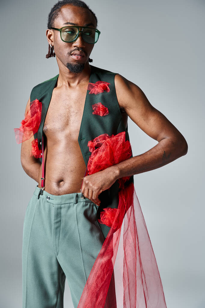 attractive african american man in stylish vest with red tulle fabric looking away, fashion concept - Photo, Image