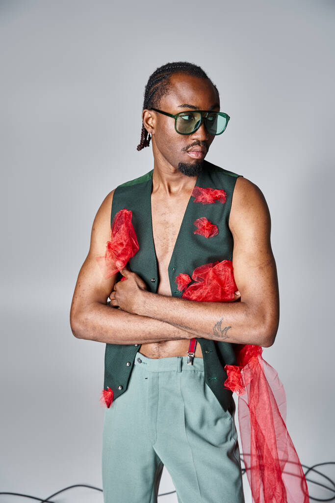 wyrafinowany afrykański amerykański model męski z czerwoną tiulową tkaniną pozującą w ruchu i odwracającą wzrok - Zdjęcie, obraz
