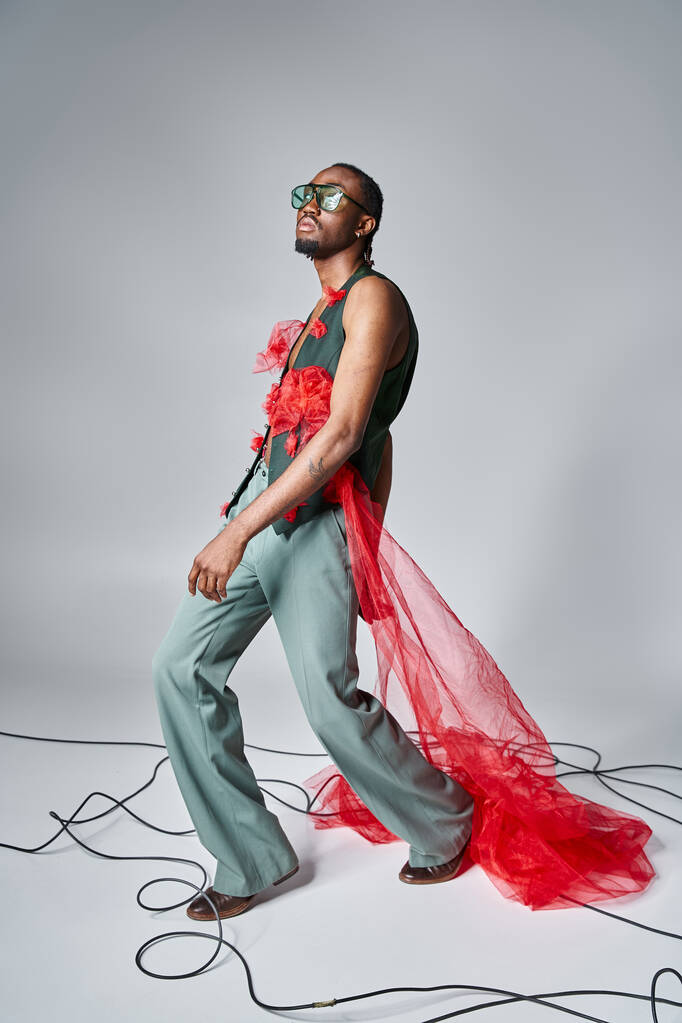 bel modello africano americano maschio con tessuto di tulle rosso in posa in movimento e guardando altrove - Foto, immagini
