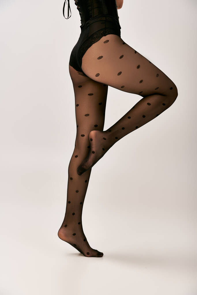 partial view of woman in corset and polka dot tights posing on white background, female buttocks - Photo, Image
