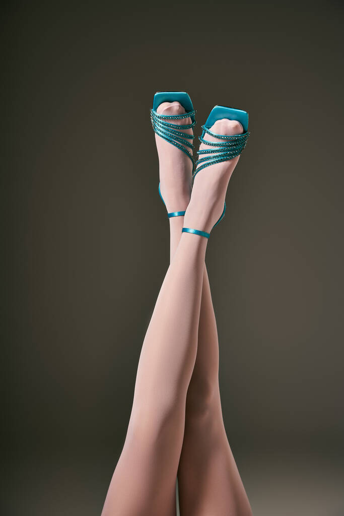 eleganti gambe incrociate femminili in collant bianco e scarpe blu su fondo grigio, calzetteria - Foto, immagini