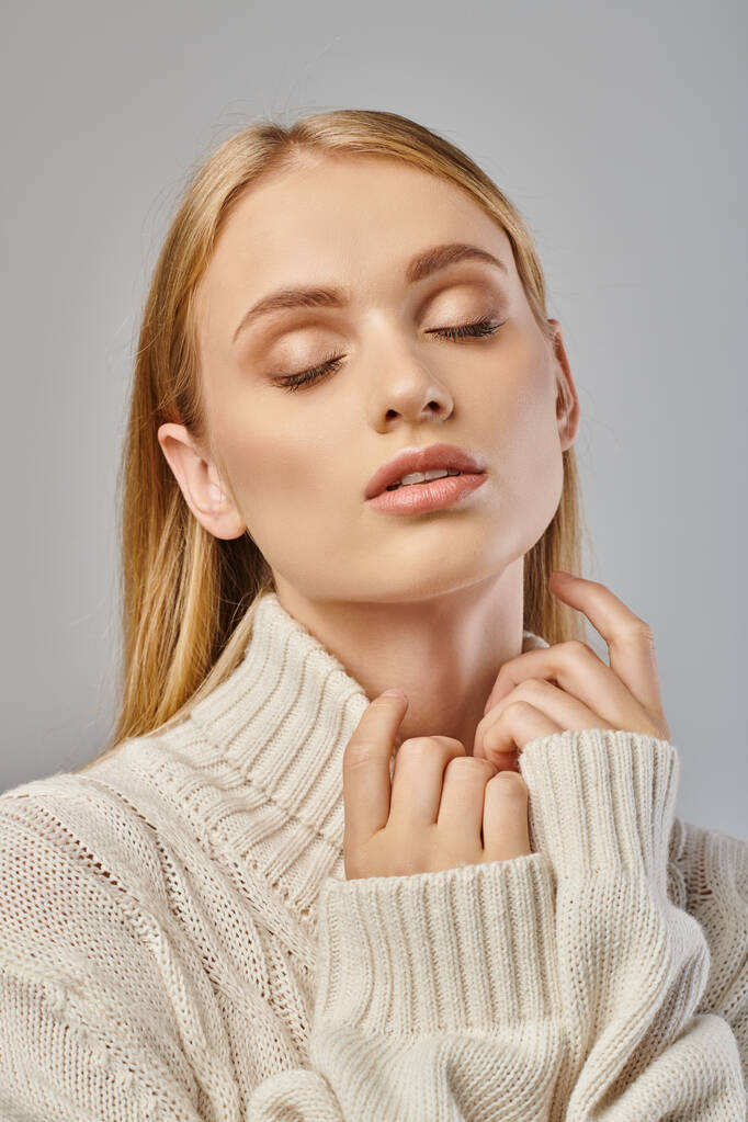 sensual blonde woman in white delicate sweater and natural makeup with closed eyes on grey, portrait - Photo, Image