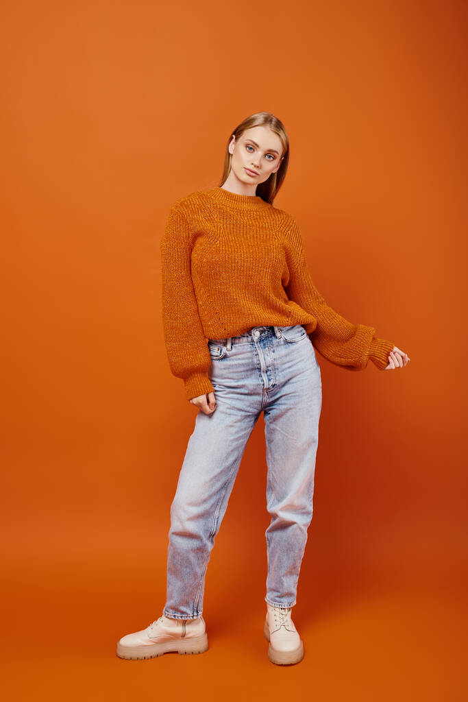 divatos szőke nő farmerban és narancssárga kötött pulóver pózol fényes háttér, téli vibrálás - Fotó, kép