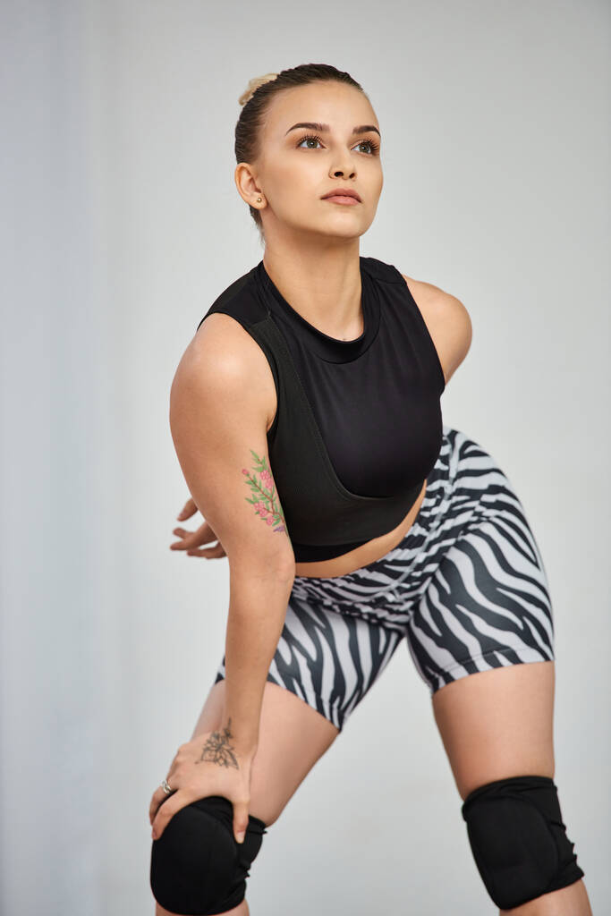 Una mujer confiada en camiseta negra y pantalones cortos de cebra balanceados en una rodilla, movimiento de coreografía - Foto, Imagen