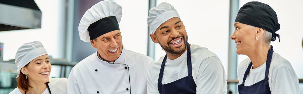молодой африканский американский шеф-повар в токе и брекетах улыбается коллегам рядом с главным поваром, баннером - Фото, изображение