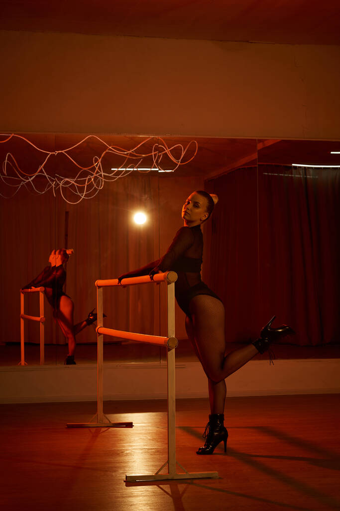 Frau im Trikot und Strumpfhose perfektioniert ihre Choreographie an der Stange, fließende Bewegungen - Foto, Bild
