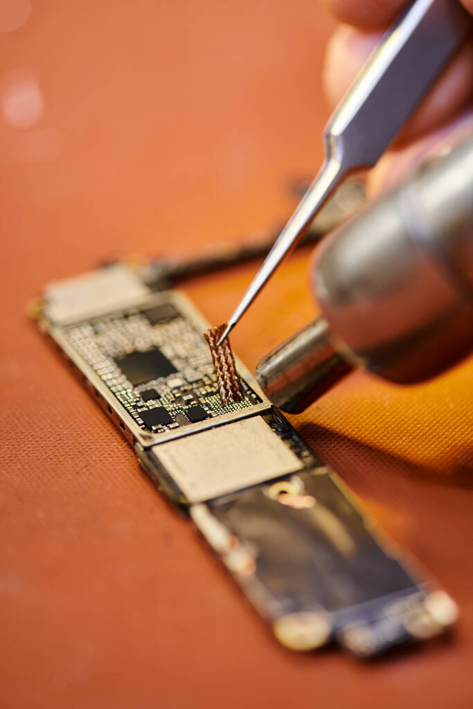 bijgesneden weergave van reparateur soldeerspaander van elektronische gadget in werkplaats, klein bedrijf - Foto, afbeelding