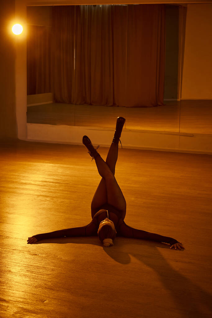 sierlijke vrouw met benen gestrekt tegen de muur als ze beweegt met vloeibaarheid en evenwicht, hoge hakken - Foto, afbeelding