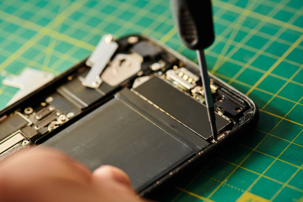 zugeschnittene Ansicht des Reparateurs, der sein Handy testet, während er in einer privaten Werkstatt arbeitet, Kleinunternehmen - Foto, Bild