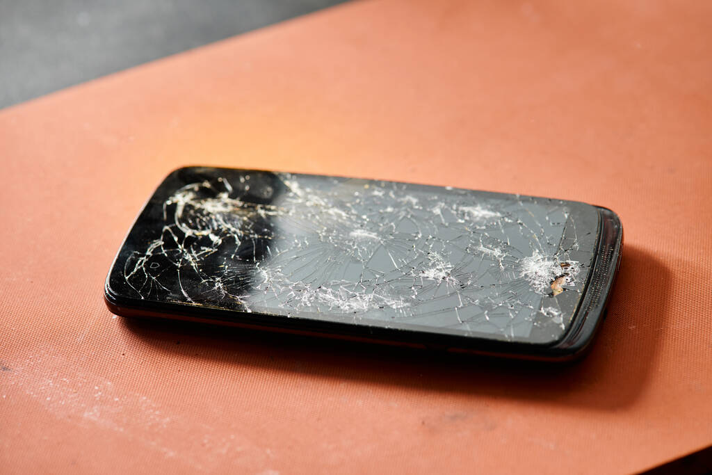 teléfono móvil moderno con pantalla táctil rota en la mesa en taller de reparación, mantenimiento de equipos - Foto, imagen