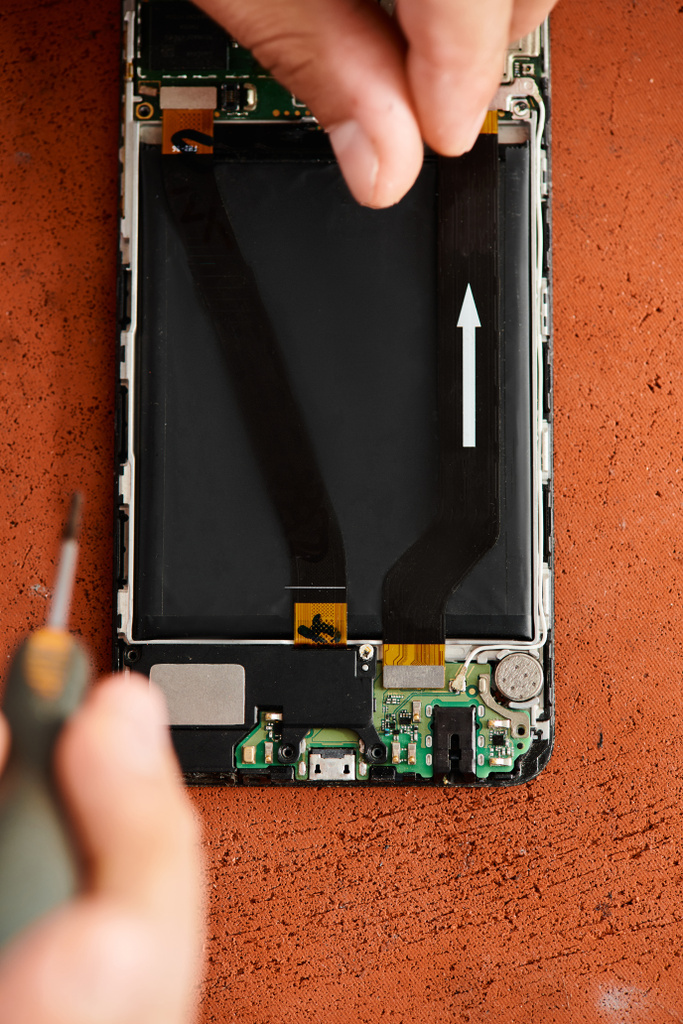 cropped view of skilled repairman removing battery from mobile phone in workshop, small business - Photo, Image