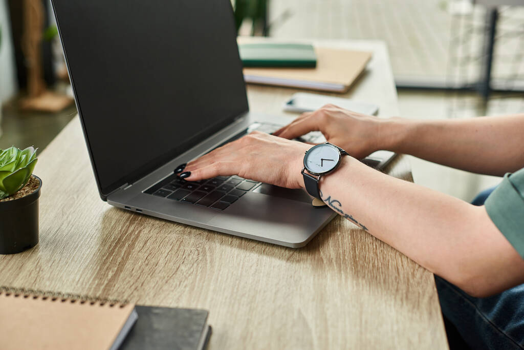 visão recortada de empresária dedicada com tatuagem e relógio de pulso trabalhando em seu laptop no escritório - Foto, Imagem