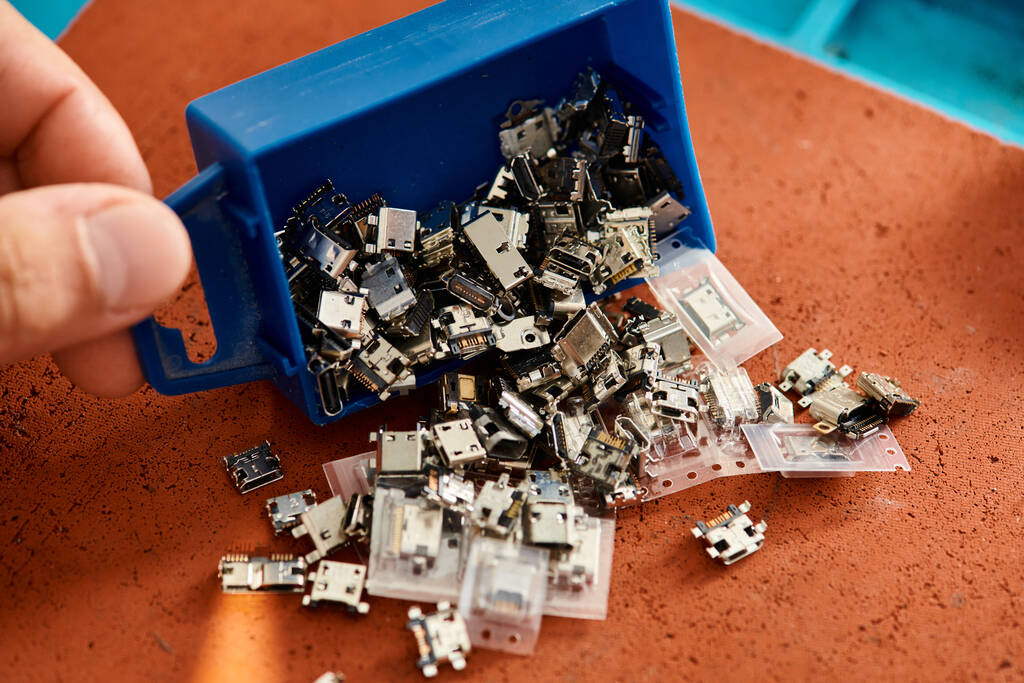 bijgesneden weergave van professionele technicus met plastic doos van verschillende onderdelen in reparatiewerkplaats - Foto, afbeelding