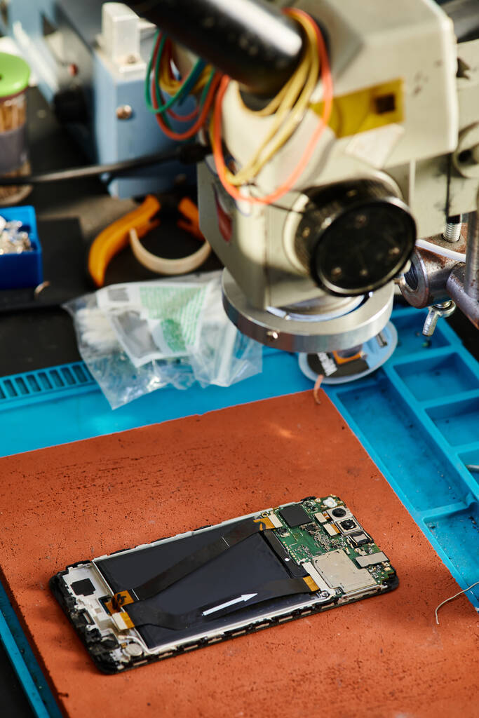 мікроскоп над мобільним телефоном на столі в майстерні по ремонту, професійне обслуговування бізнесу - Фото, зображення