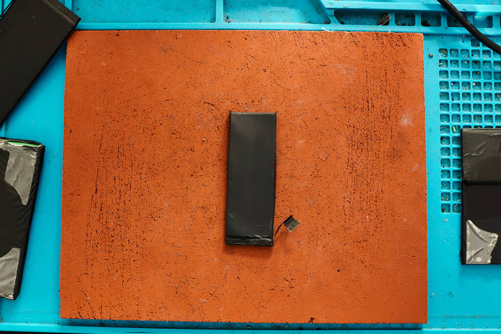 bovenaanzicht van nieuwe telefoonbatterij op werktafel in reparatiewerkplaats, onderhoudsconcept - Foto, afbeelding
