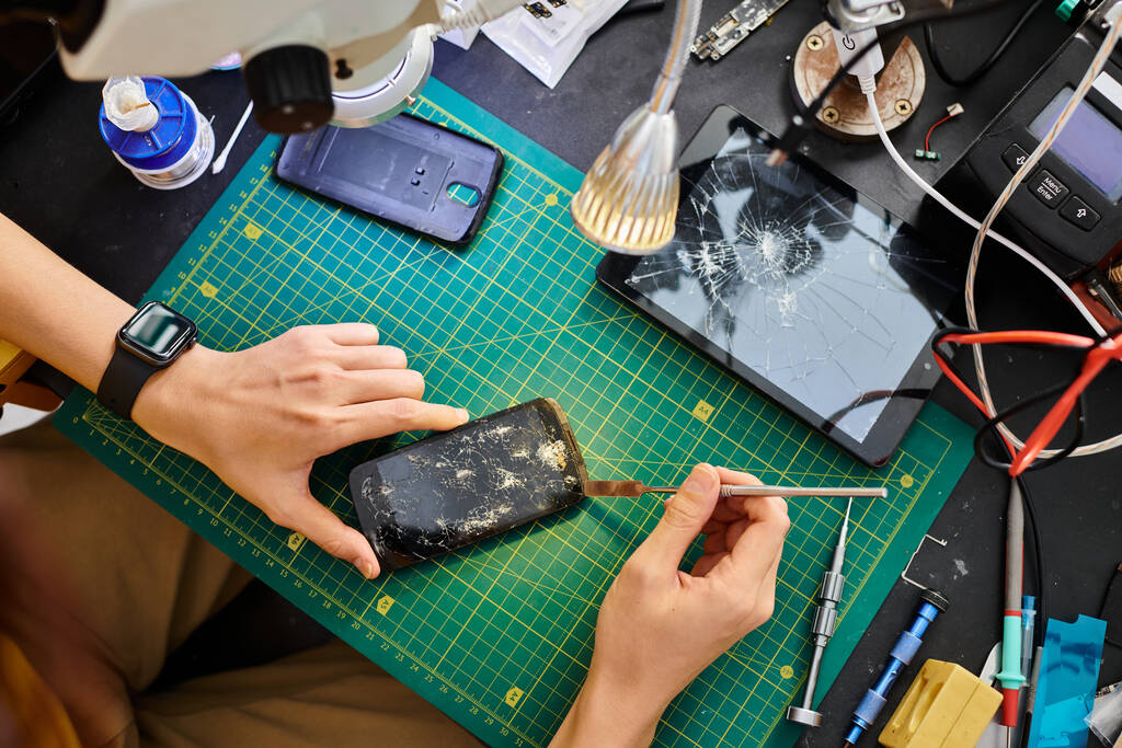 oříznutý pohled technika odpojujícího rozbitý dotykový displej smartphonu v opravárenské dílně - Fotografie, Obrázek