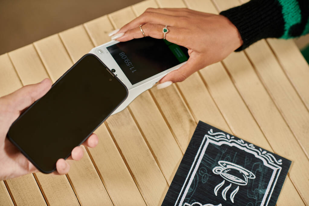 paiement par téléphone mobile, vue recadrée de la femme tenant son smartphone près du lecteur de carte dans un café végétalien - Photo, image