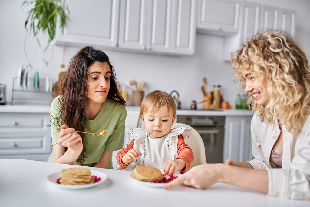wesoły bonded lesbijskie para jedząc śniadanie z ich mała ładna córka, koncepcja rodziny - Zdjęcie, obraz