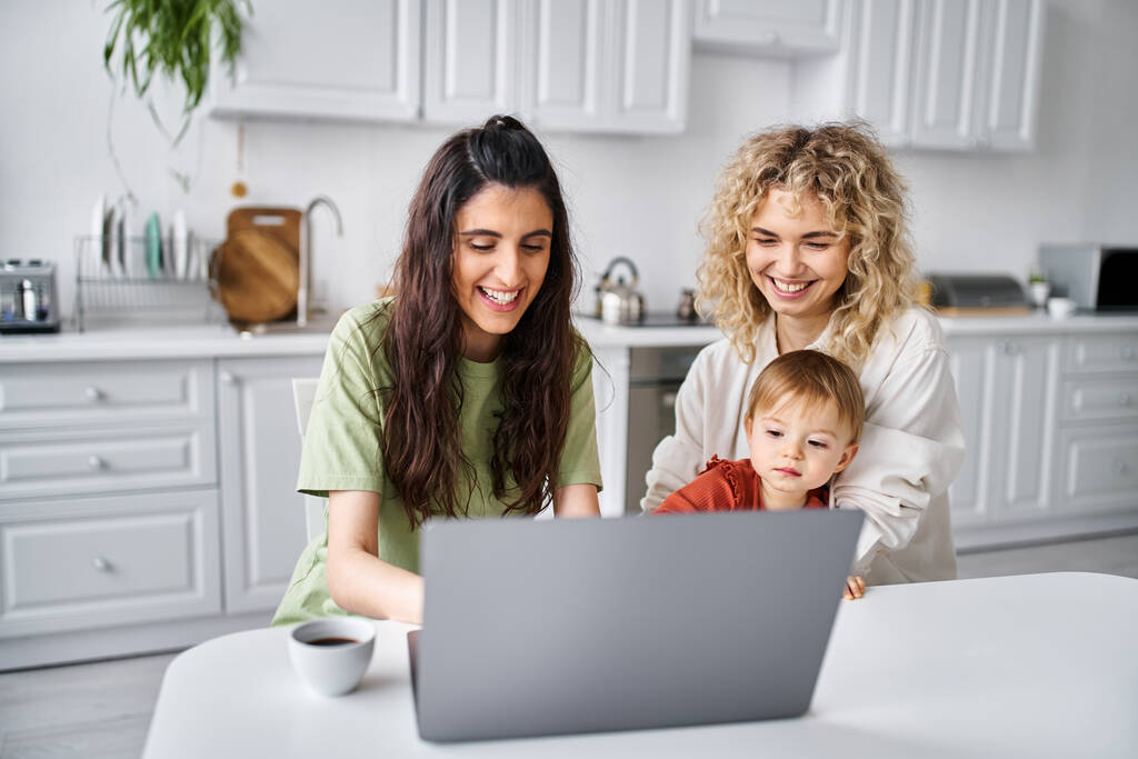 feliz casal lgbt assistindo filmes com sua filha no laptop na cozinha, parentalidade moderna - Foto, Imagem