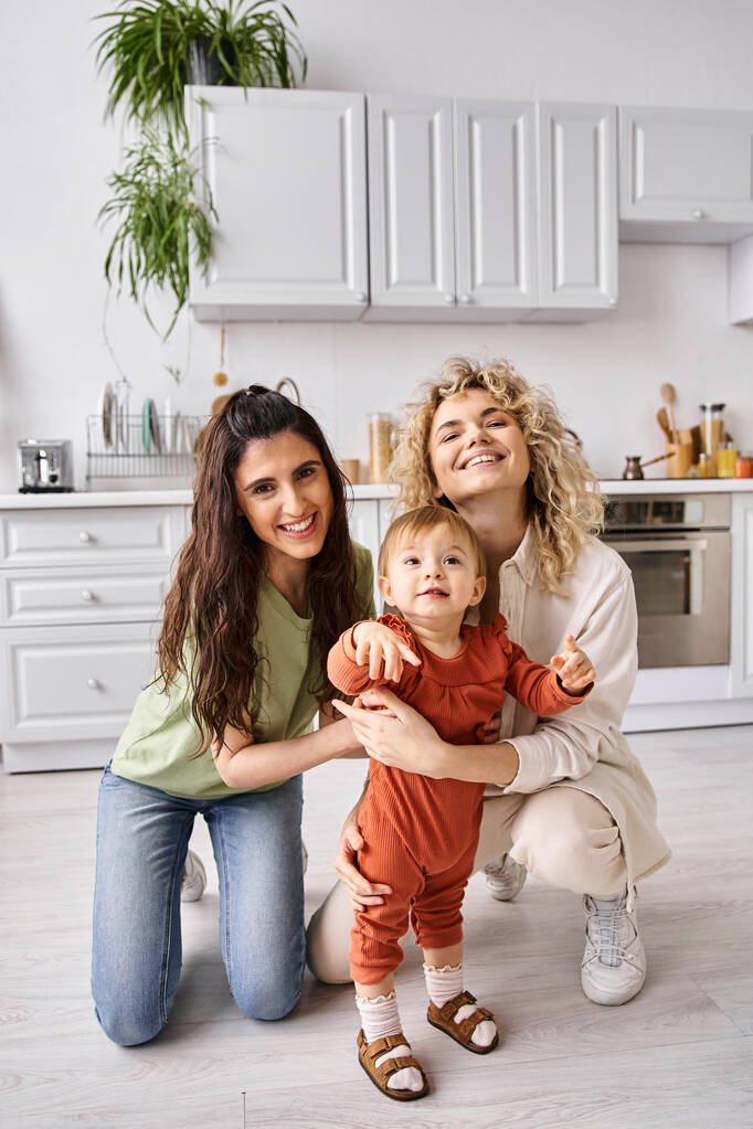 affascinante jolly lesbica coppia in homewear trascorrere del tempo insieme con il loro bambino figlia - Foto, immagini
