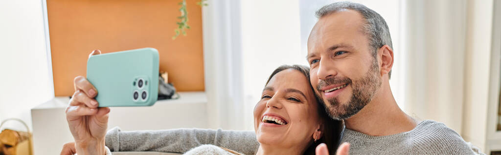 gelukkig vrouw nemen van foto op smartphone met man in woonkamer, kindvrij paar, banner - Foto, afbeelding