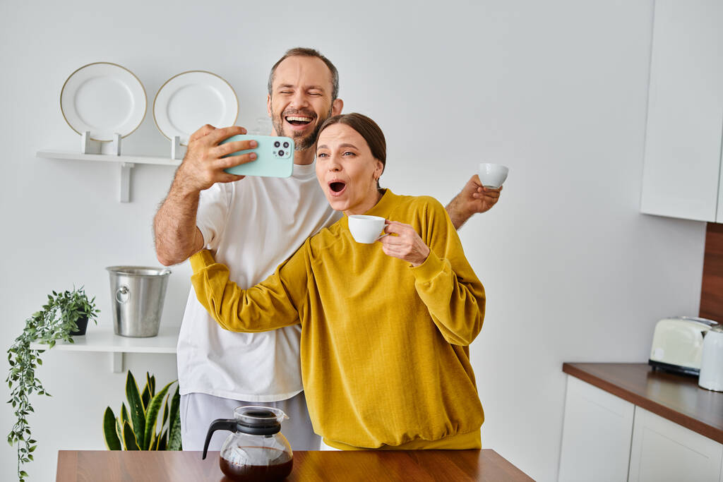 boldog gyermek-mentes pár szórakozás és szelfi reggeli kávé a modern konyhában - Fotó, kép