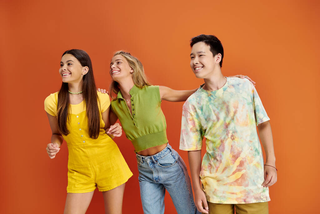veselý multiraciální teenageři v pulzující oblečení baví spolu a dívá se jinam, přátelství den - Fotografie, Obrázek