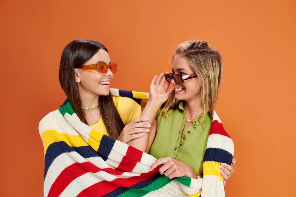 fröhliche entzückende Teenager-Mädchen mit Sonnenbrille, die sich umarmen und mit einer Decke bedecken, Freundschaftstag - Foto, Bild