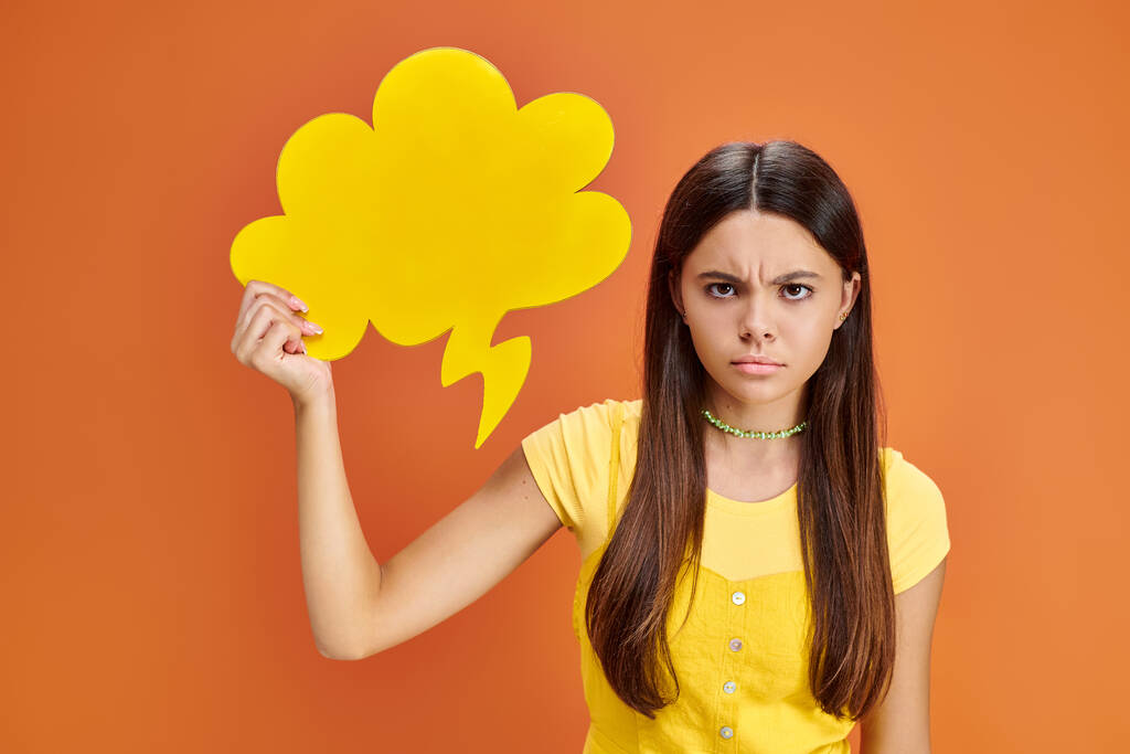 menina adolescente frustrada em camiseta vibrante posando com bolha de pensamento amarelo e olhando para a câmera - Foto, Imagem