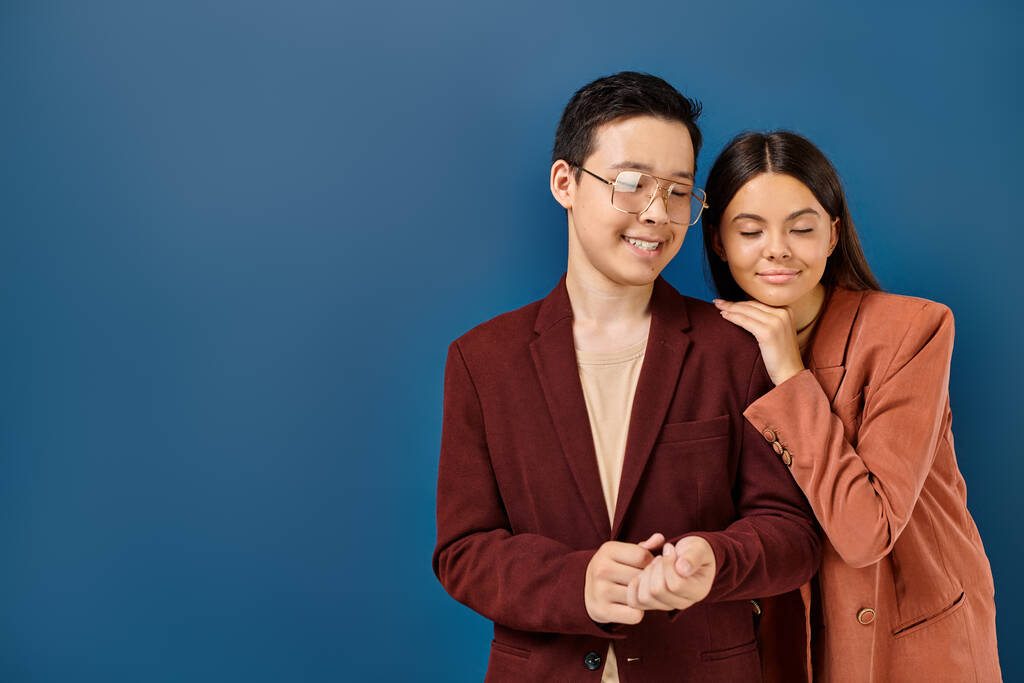 fröhlich-elegante Teenager in modischen Blazern posieren gemeinsam vor dunkelblauem Hintergrund - Foto, Bild