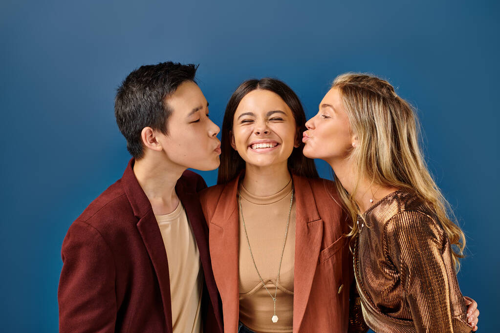 adorable interracial teenage boy and girl kissing their jolly friend in cheek, friendship day - Photo, Image