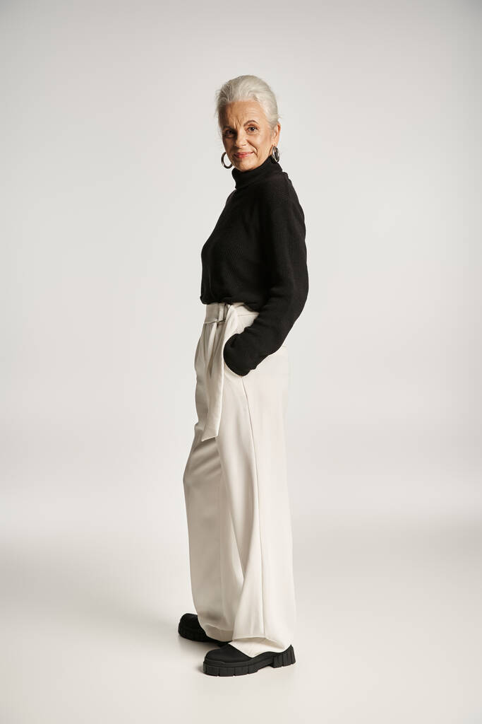 comprimento total de feliz mulher de negócios de meia idade em traje elegante posando com as mãos nos bolsos - Foto, Imagem
