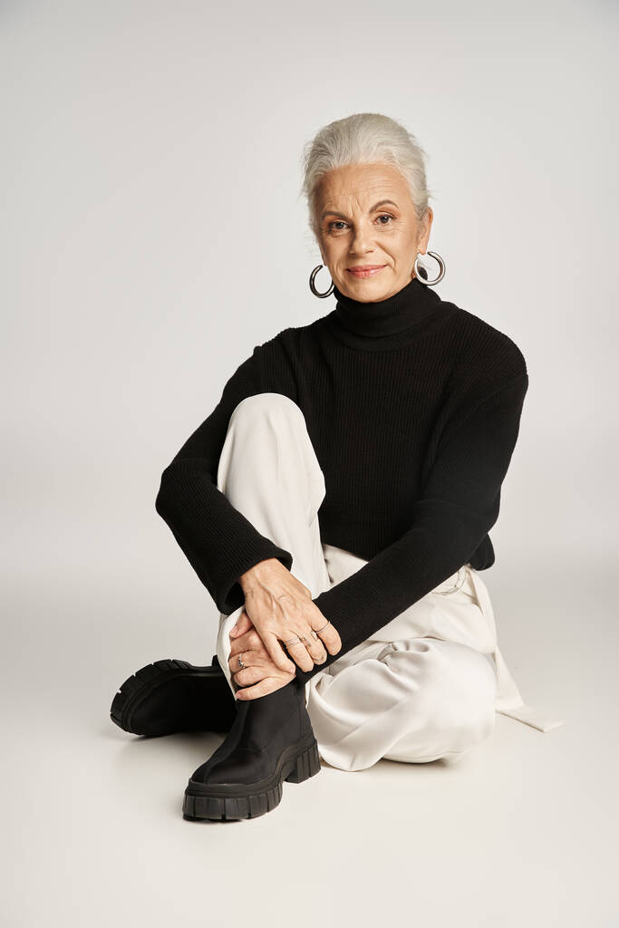 heureuse femme d'affaires d'âge moyen en élégante tenue décontractée intelligente assise sur fond gris - Photo, image
