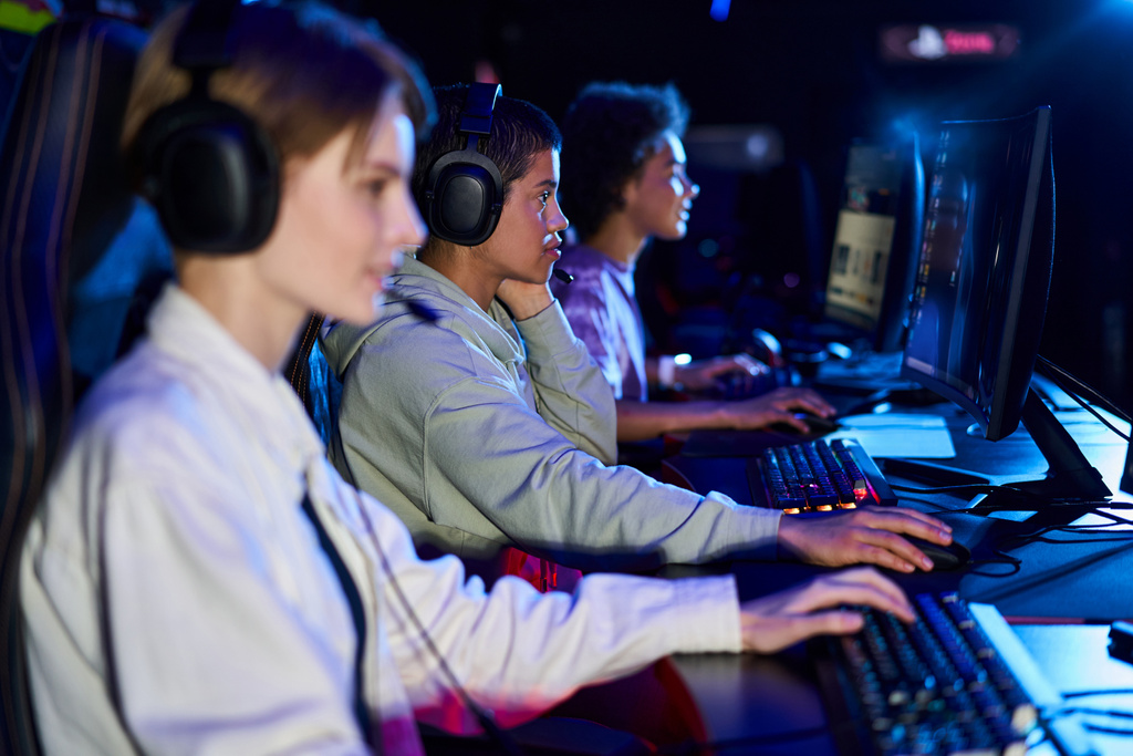 Diversas y jóvenes mujeres interracial que participan en juegos de ciberdeporte, utilizando computadoras y auriculares - Foto, Imagen