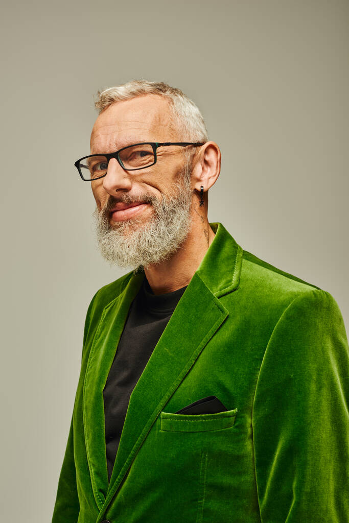 カメラで笑顔のアクセサリーが付いている緑のスタイリッシュなブレーザーのハンサムな灰色ひげの成熟した男 - 写真・画像
